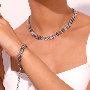 Detail shot of silver stainless steel watch-band style necklace and bracelet set on model