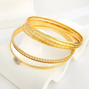 Detail of gold-plated alloy bangles with diamond-cut textures and rhinestone accents