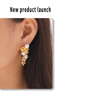 Detailed view of irregular white pearls and gold bead cluster earrings on a model