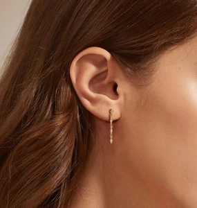 Detailed view of elegant gold-plated chain earrings with cubic zirconia on a female model
