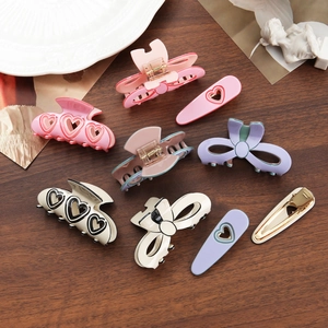 Bow hair claw clips and heart-shaped hairpins set on a wooden table in Korean style