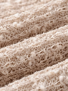 Macro shot of off-white knitted fabric featuring soft textured pom-pom details and fringe