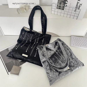 Detailed overhead view of grey and black velvet tote bags with white pearl embellishments