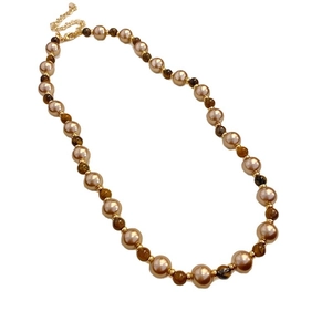 Elegant gold necklace with lustrous pearls and tiger eye beads on a white background