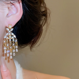 Macro shot of long gold tassel earrings with yellow square and white drop stones