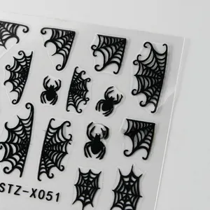 Macro detail of Halloween nail stickers featuring black spiders and spiderweb designs