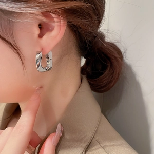 Gros plan de boucles d'oreilles géométriques argentées en forme de U sur un modèle