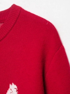 Dettaglio del maglione in maglia rossa con scollo a girocollo e motivo jacquard bianco