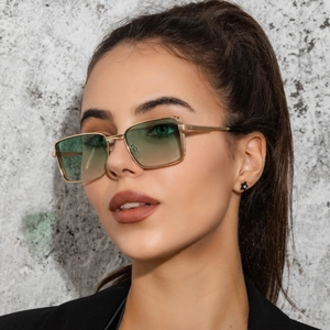 Close-up of golden square metal sunglasses with light green gradient lenses on a model