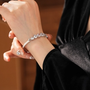 Close-up of elegant silver bangle with wavy circular zircon settings on a wrist