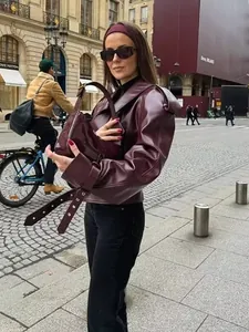 Detail of burgundy faux leather jacket with stand collar and matching handbag on model