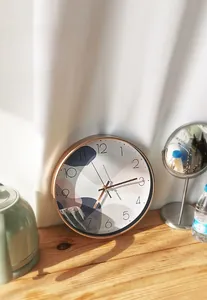 Artistic silent wall clock with gold frame on a wooden desk in a warm home setting