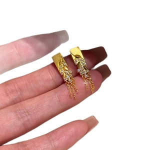 Boucles d'oreilles épi de blé plaquées or avec zircons et pompons en présentation main