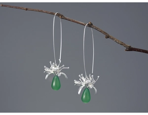 Macro view of sterling silver spider lily earrings with green chalcedony beads on branch