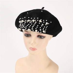 Detailed close-up of white pearls and sparkling rhinestones on a black cashmere beret