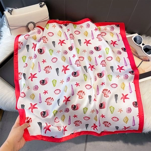 Gros plan d'un foulard carré en soie imprimé avec motifs d'étoiles de mer et coquillages