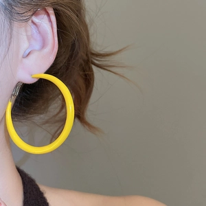 Gros plan d'un mannequin portant de grandes créoles rondes jaunes au style minimaliste moderne