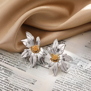 Macro detail of silver flower earrings with golden center on vintage silk background