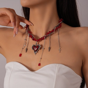 Close-up of Gothic red heart cross necklace with tassel charms on model neck