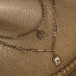 Macro shot of silver-colored layered necklace with starburst and rectangular pendants