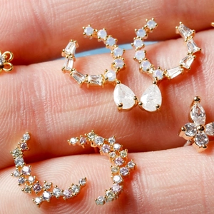 Macro shot of 18K gold earrings with moon and flower shapes featuring sparkling zircons