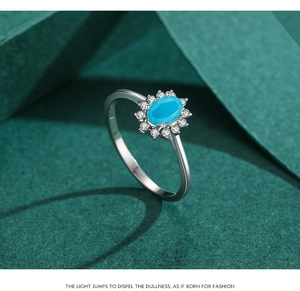 Macro shot of silver ring featuring an oval blue stone with pavé zircon halo detail