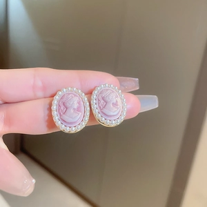 Close-up of vintage pink cameo earrings featuring an oval relief portrait and pearl trim