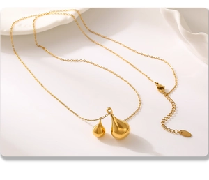Detailed view of dual teardrop gold pendants on a delicate link chain with lobster clasp