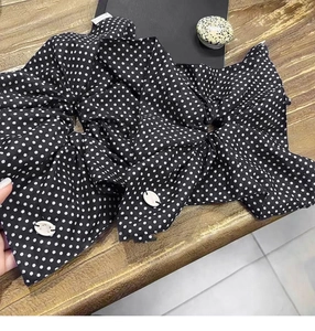 Detailed close-up of polka dot fabric hair scrunchie with white resin accessory
