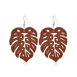 Detailed view of monstera leaf wooden earrings with silver metal hooks on white background