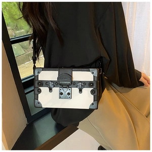 Detail of vintage cream box bag with black trim, rivets and a silver metal lock
