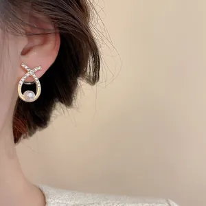 Close-up of elegant gold earrings with round pearls and sparkling zircon accents
