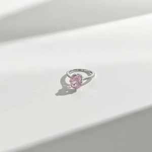 Macro detail of oval pink gemstone ring featuring a silver band with pavé crystals