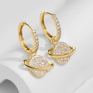 Macro shot of gold Saturn earrings with micro-inlaid zircons on a white display