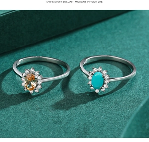 Detail of silver rings featuring turquoise and orange gems with a diamond halo design