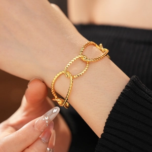 Close-up of gold plated irregular oval link bracelet on a wrist with black sweater