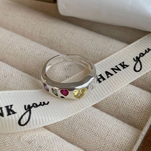 Detail of silver open ring with colorful heart-shaped zircons in a beige jewelry box