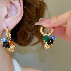 Detail of vintage beaded hoop earrings with colorful stones and polished gold metal charms