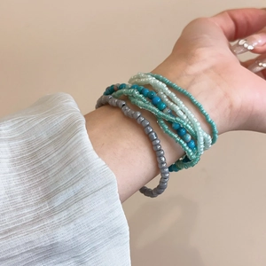 Detail of bohemian seven-piece seed bead bracelets in turquoise and mint on a wrist