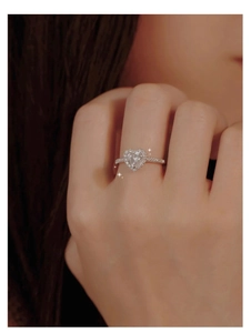 Close-up of heart-shaped moissanite ring with halo and pave diamonds on hand