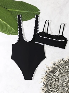 Detailed flat lay of black two-piece swimsuit with white scalloped trim and summer straw hat