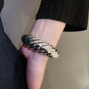 Close-up of a silver twisted texture wide cuff bracelet on a model wrist