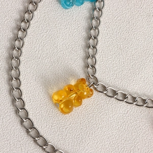 Detailed close-up of a silver metal chain necklace featuring an amber resin bear charm