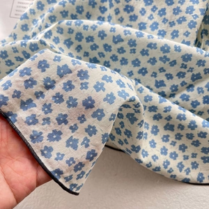 Detail of light cotton linen scarf with blue floral pattern showing fabric texture