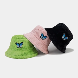 Close-up of butterfly embroidery detail and plush faux fur texture on the bucket hats