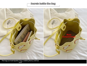 Detail view of the yellow drawstring bucket bag showing interior space and orange embroidery