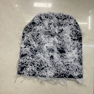 Detailed shot of black and white camo knit beanie featuring trendy fringe and distressed holes