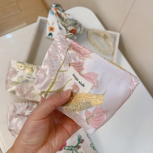 Close-up of a floral jacquard mini storage pouch with a simple wish label detail
