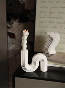 Close-up of white wavy ceramic candle holder with fine vertical stripe texture and candle
