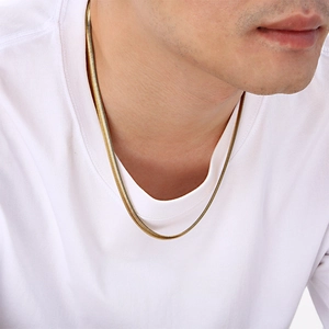 Close-up of a men's gold snake bone chain necklace worn over a white T-shirt